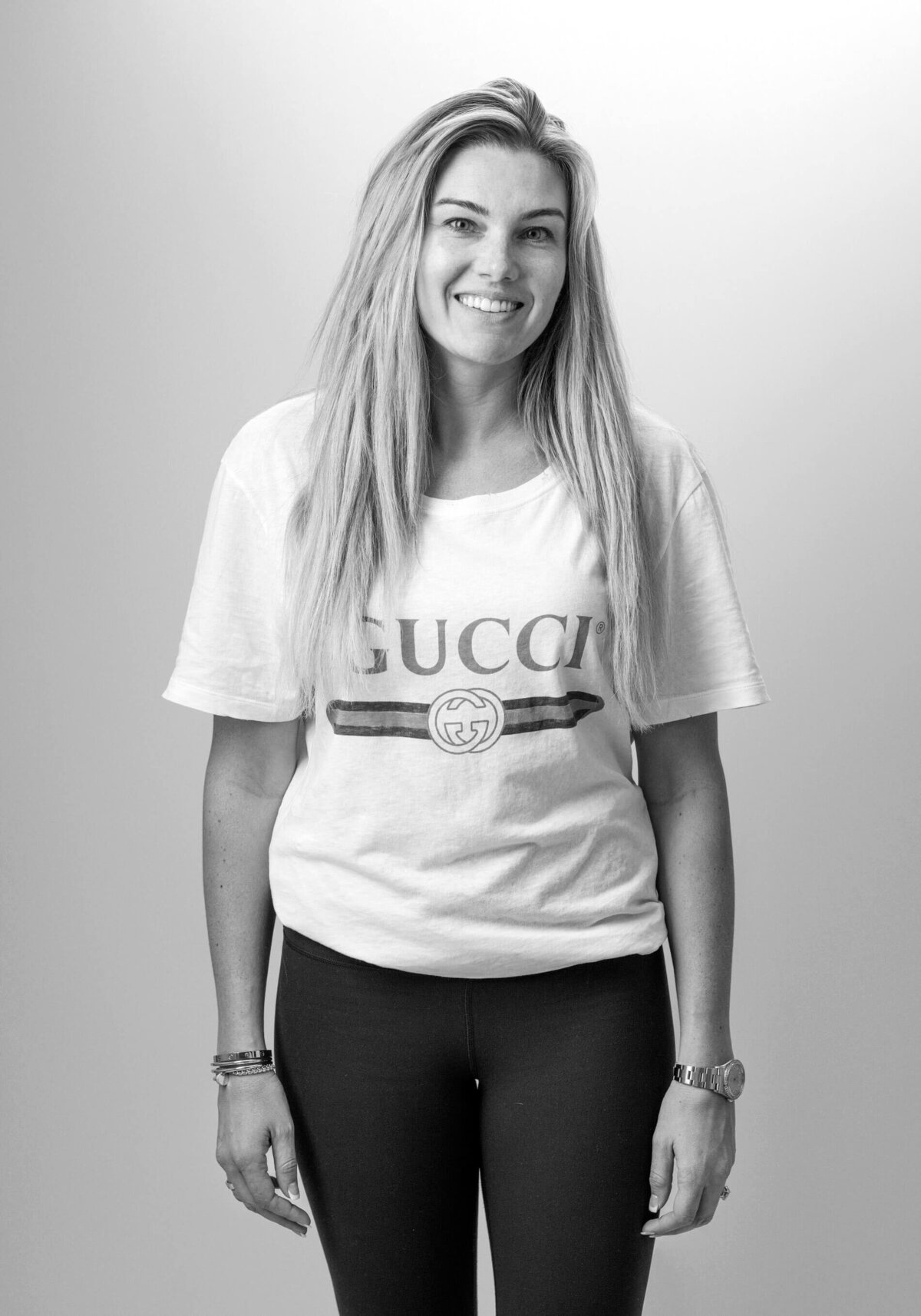Before shot of a woman wearing a Gucci T-shirt, standing confidently with a soft smile.