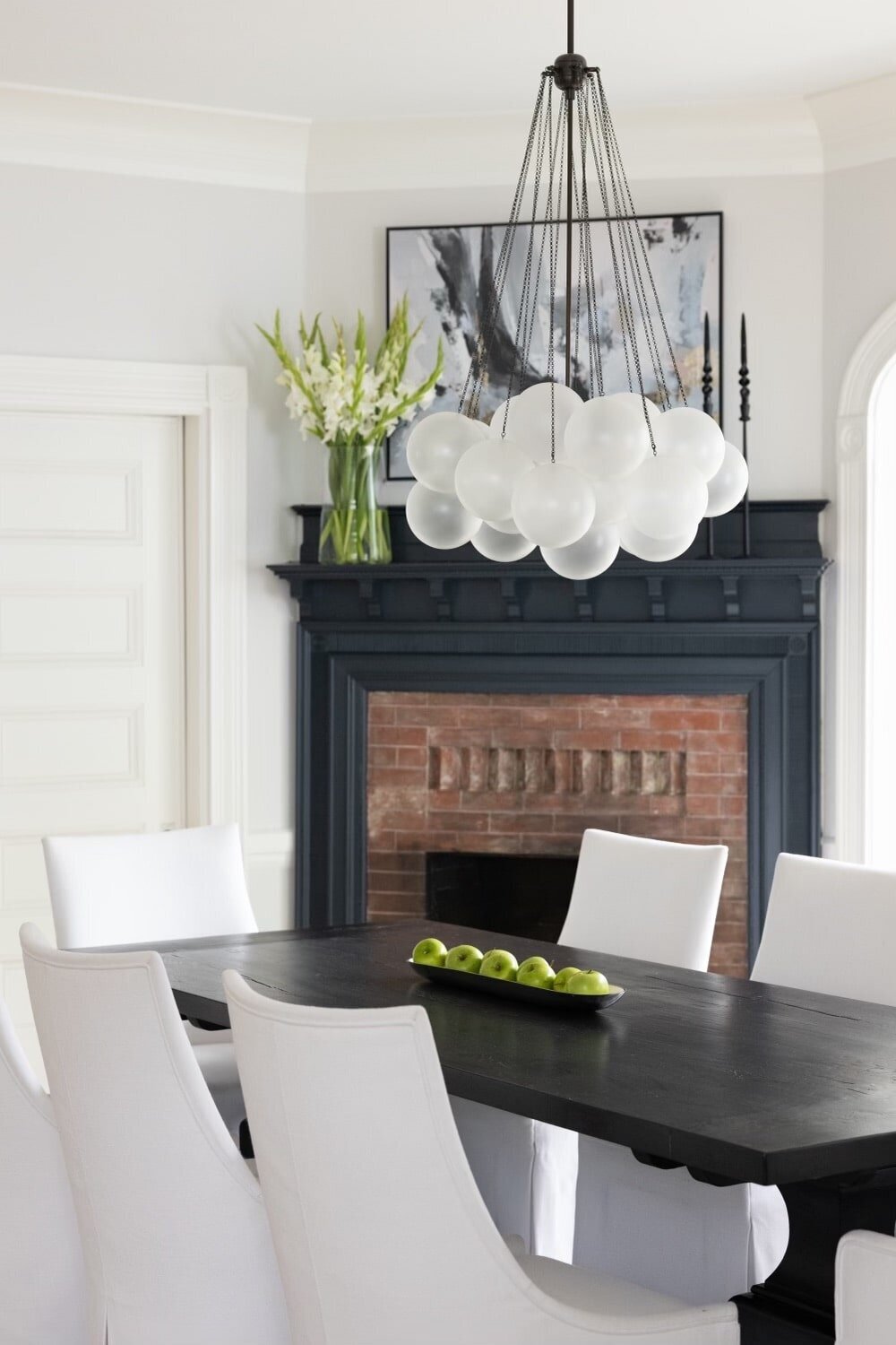 Historic dining room in Newton featuring a black fireplace, modern chandelier, and classic architectural details