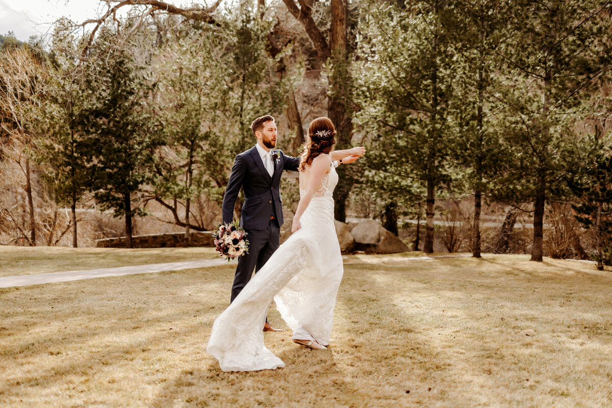 Husband twirling his new bride on a large grassy lawn in Boulder Colorado