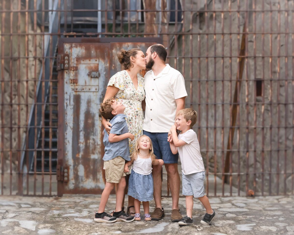 family photo mom and dad kissing in front of old prision in McKinney Texas captured by Allison Amores Photography