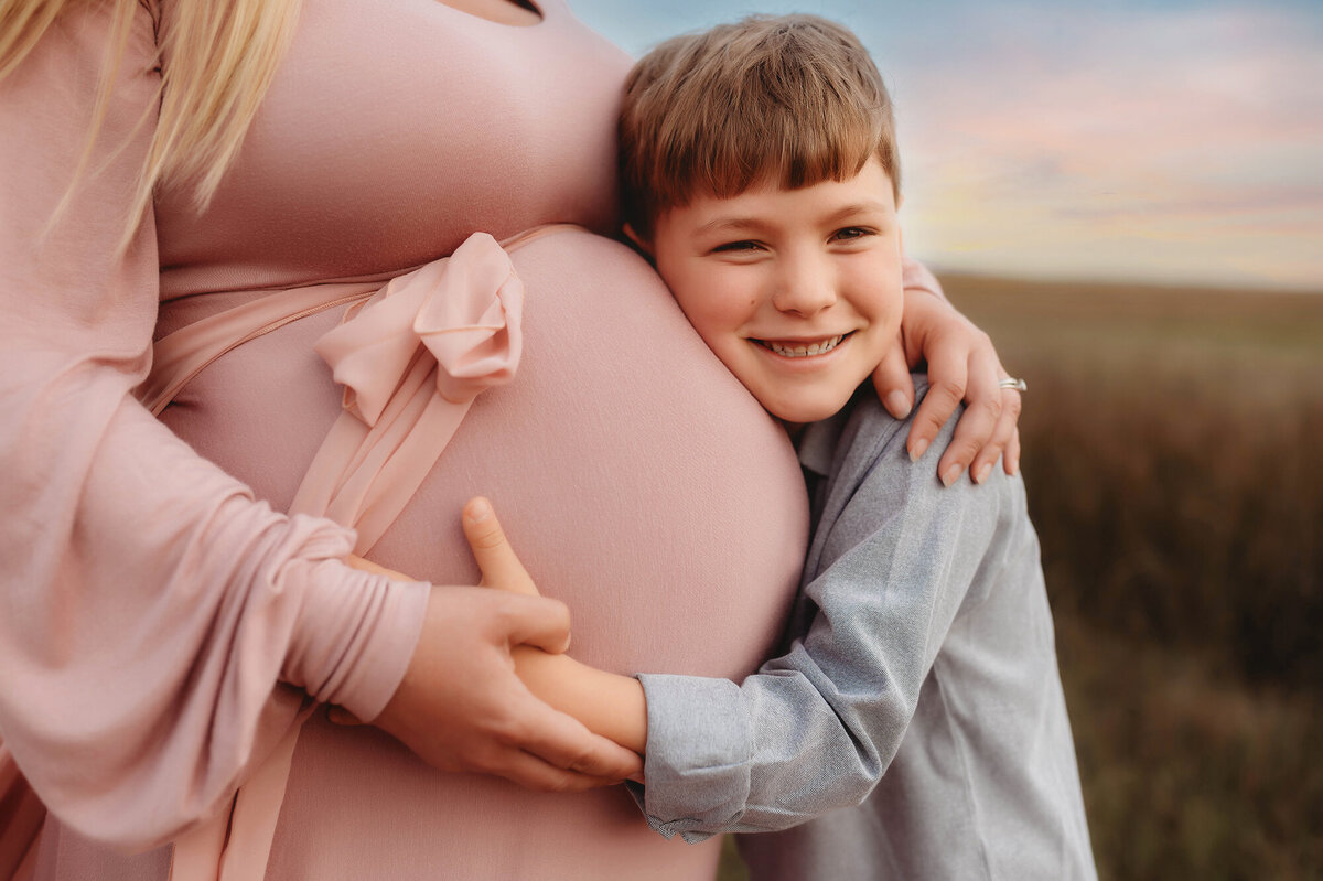 Young boy hugs his mother's pregnant belly during Maternity Photoshoot in Charleston, SC.