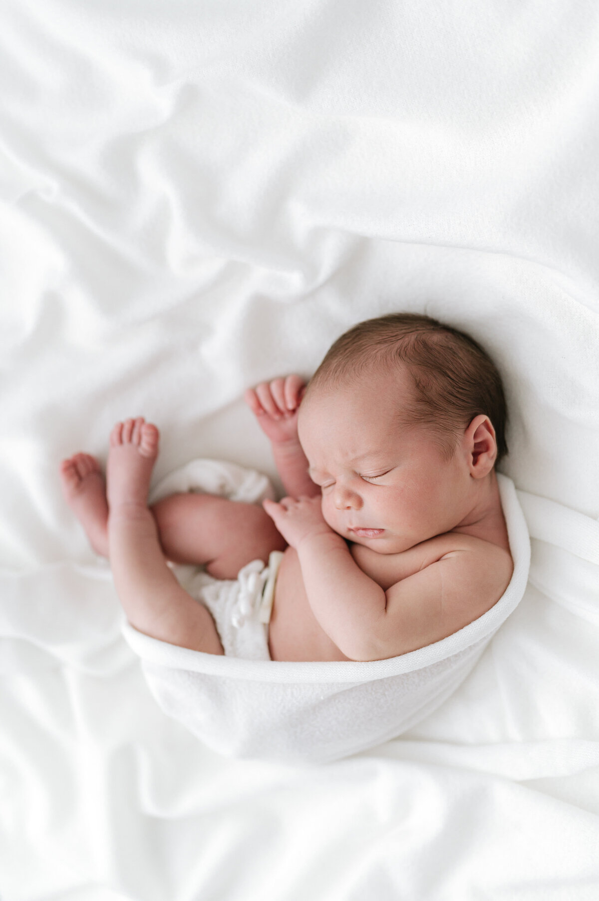 Baby wrapped and curled up in a newborn photography shoot