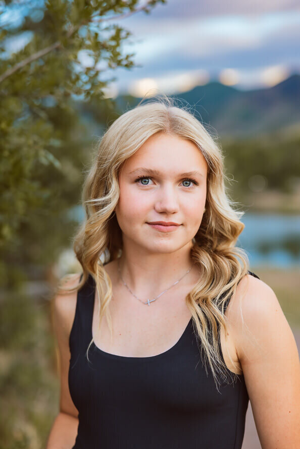 Girl has soft smile with mountains in the background.