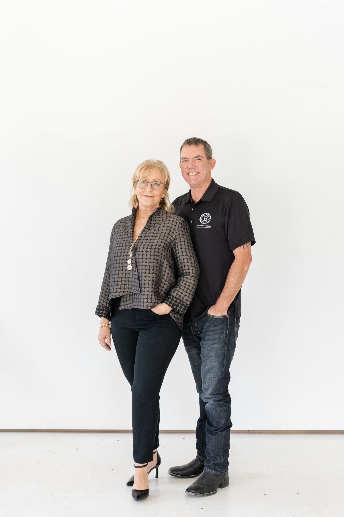 Husband and wife standing in front of white backdrop for real estate branding session at Sweenshots Studio in Houston