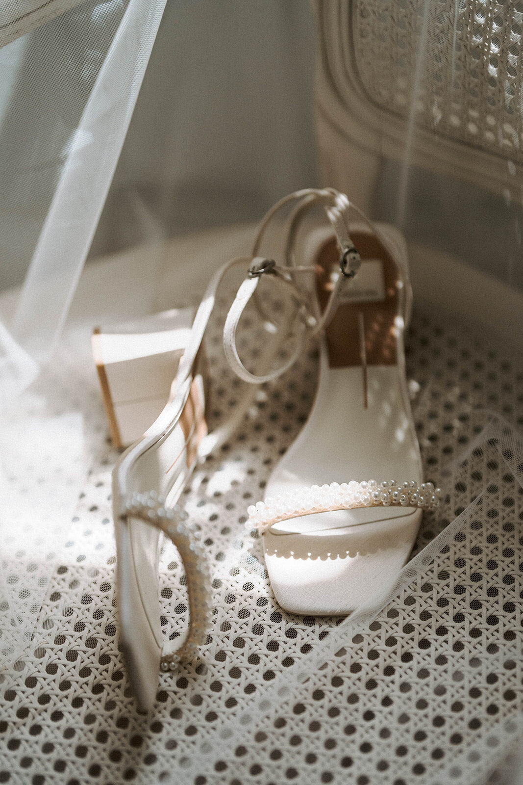 white peal bridal chunky heels on white canned chair with veil draped