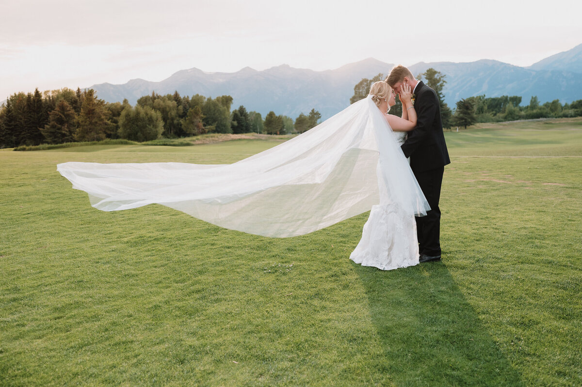 Bride and groom on golf course during golden hour with mountains in background