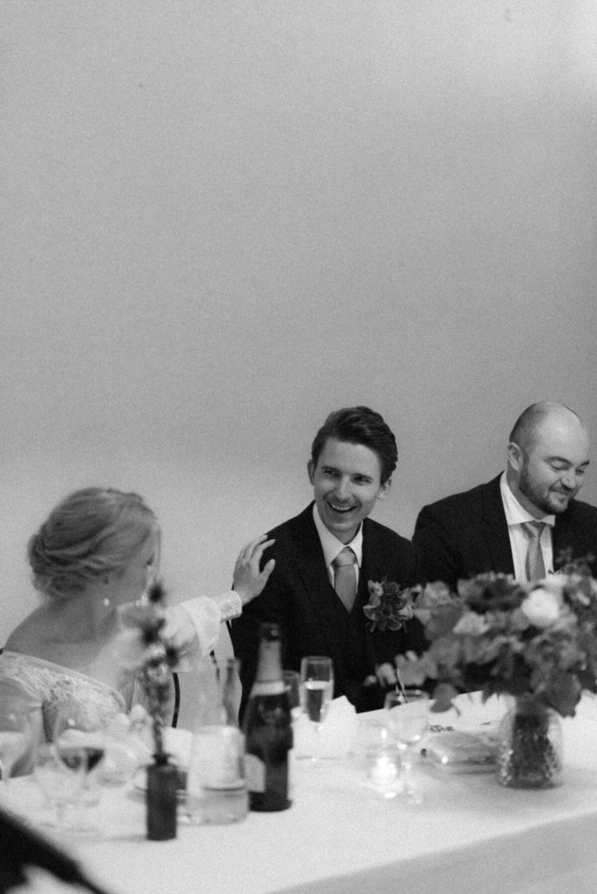 A documentary wedding  photo of the bride and groom laughing at a speech in Oitbacka gård captured by wedding photographer Hannika Gabrielsson in Finland