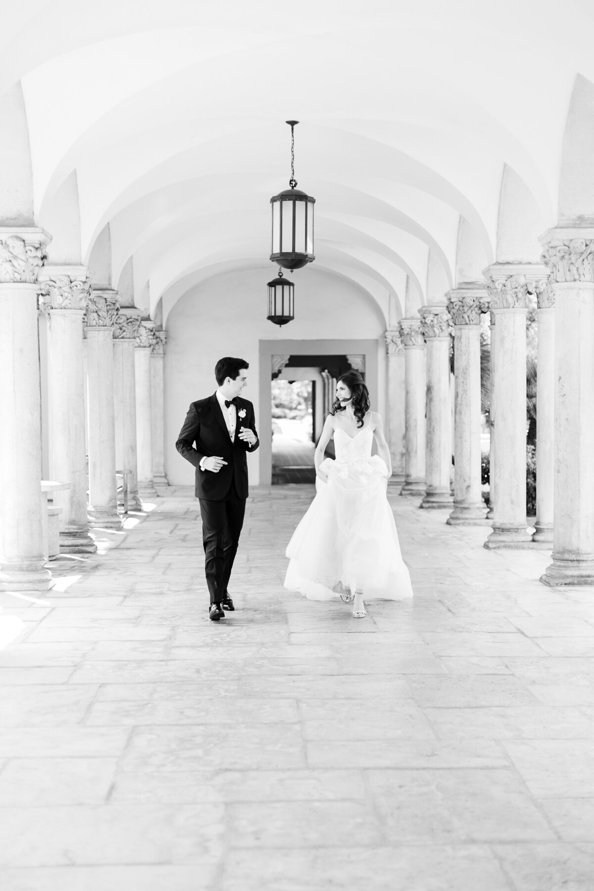 Bride and groom stroll down arched walkway on their wedding day