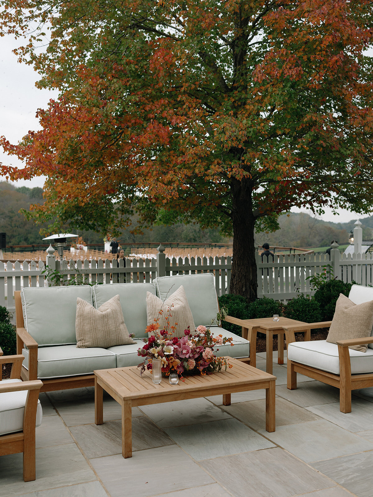 Sculptural ikebana and meadow arrangements decorate the cocktail hour for private estate wedding in Tennessee hills.Clear top tent build out for fall wedding reception in Tennessee hills.  Trailing bar arrangements and floral meadow centerpieces for autumnal wedding reception. Orchids, bittersweet berries, butterfly ranunculus, and tulips are highlighted. Artistic fall color palette in copper, gold, ruby, lavender, and rust. Design by Rosemary & Finch Floral Design in Nashville, TN.
