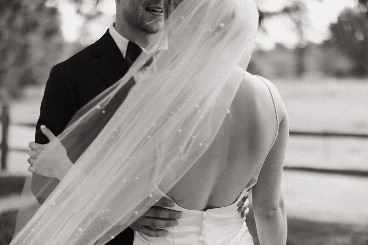 Black and white image of faceless bride and groom with long vail