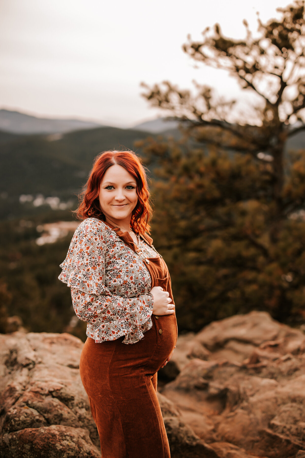 pregnant mom weras orange maternity overalls in the mountains