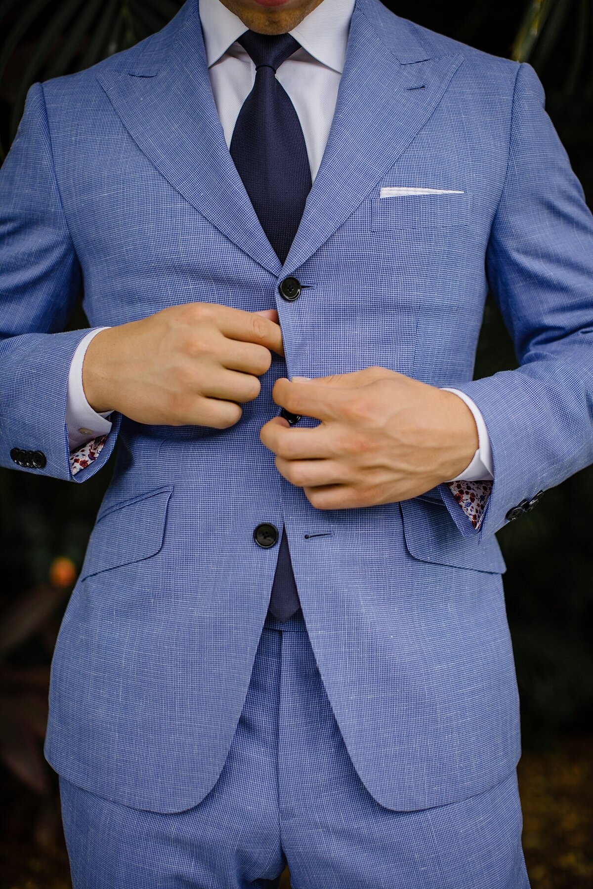 groom buttoning blue suit
