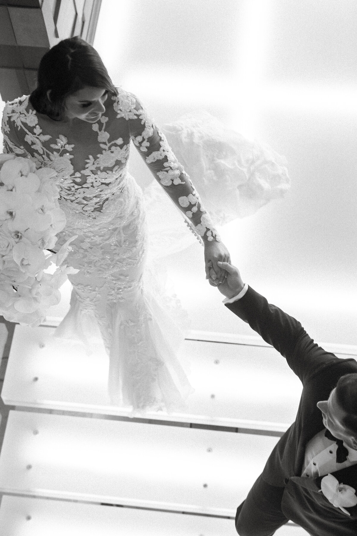 Groom guides his bride down stairs on their wedding day