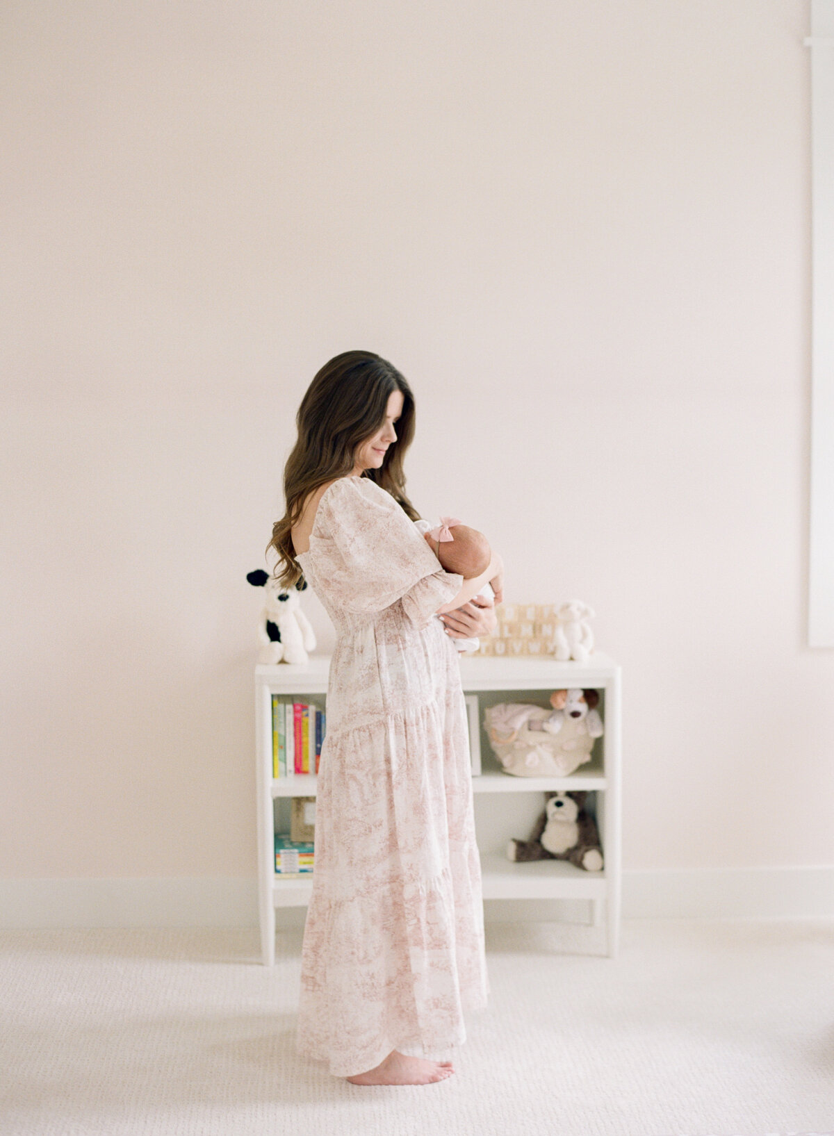 Mom stands and holds her daughter for a newborn session. Image by Raleigh newborn photographer A.J. Dunlap Photography.