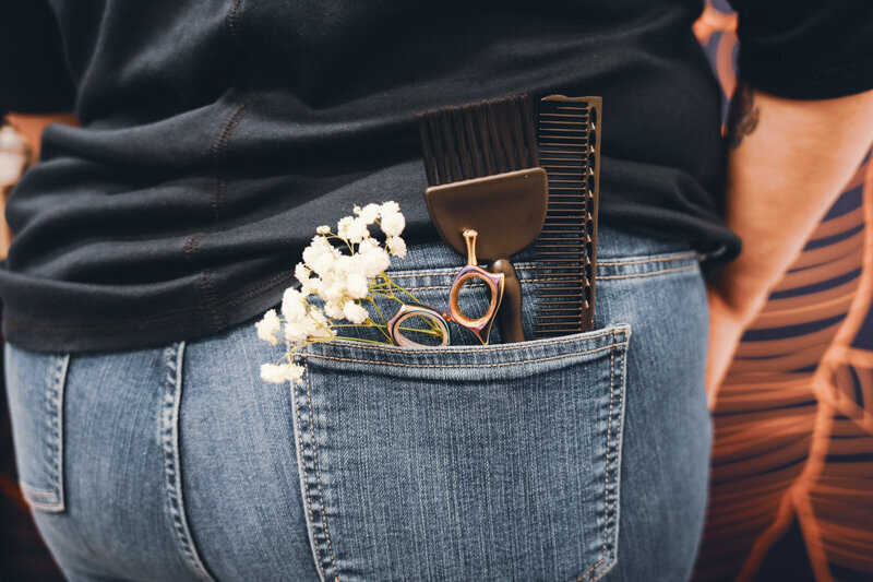 Backpocket of hairstylist with flowers and hairstyling tools in the pocket
