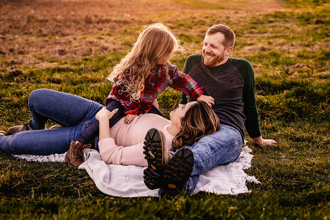 Family sitting on blanket in field at Wagon Hill in Durham NH by Lisa Smith Photography