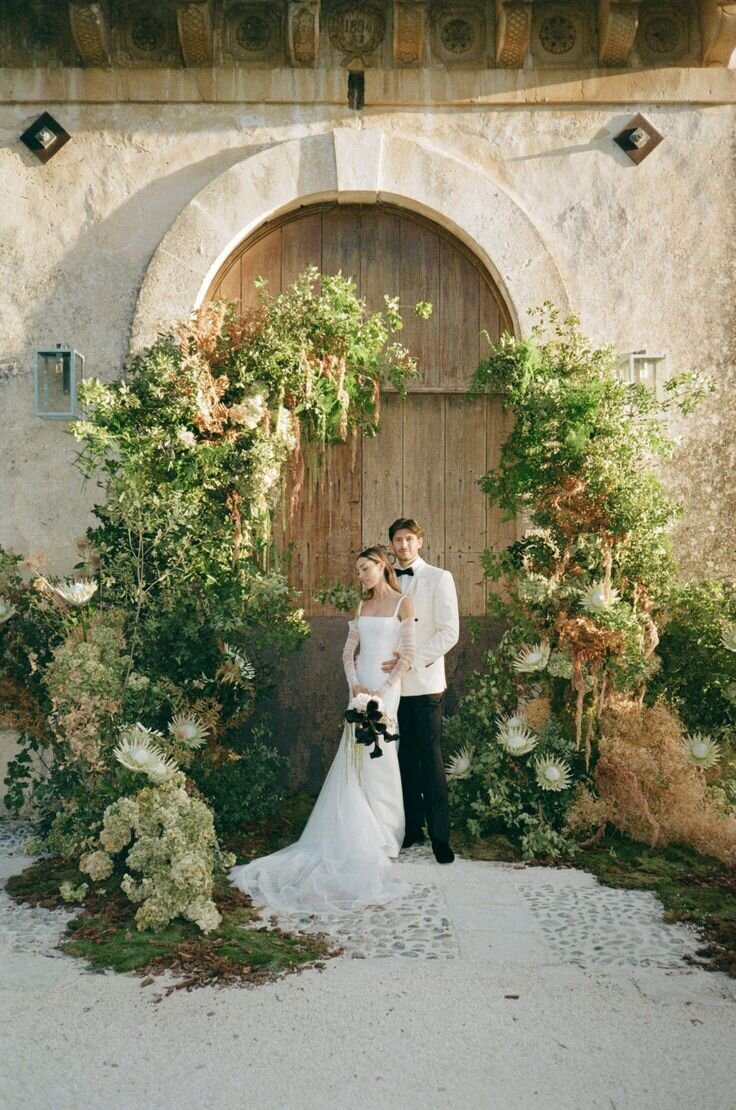 Editorial wedding portrait with floral arch and textured stone backdrop, styled as inspiration for a Wrightsville Manor ceremony