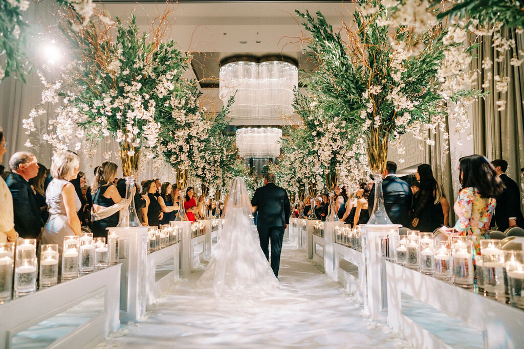 Photo of the bride walking down the elegantly decorated aisle. 