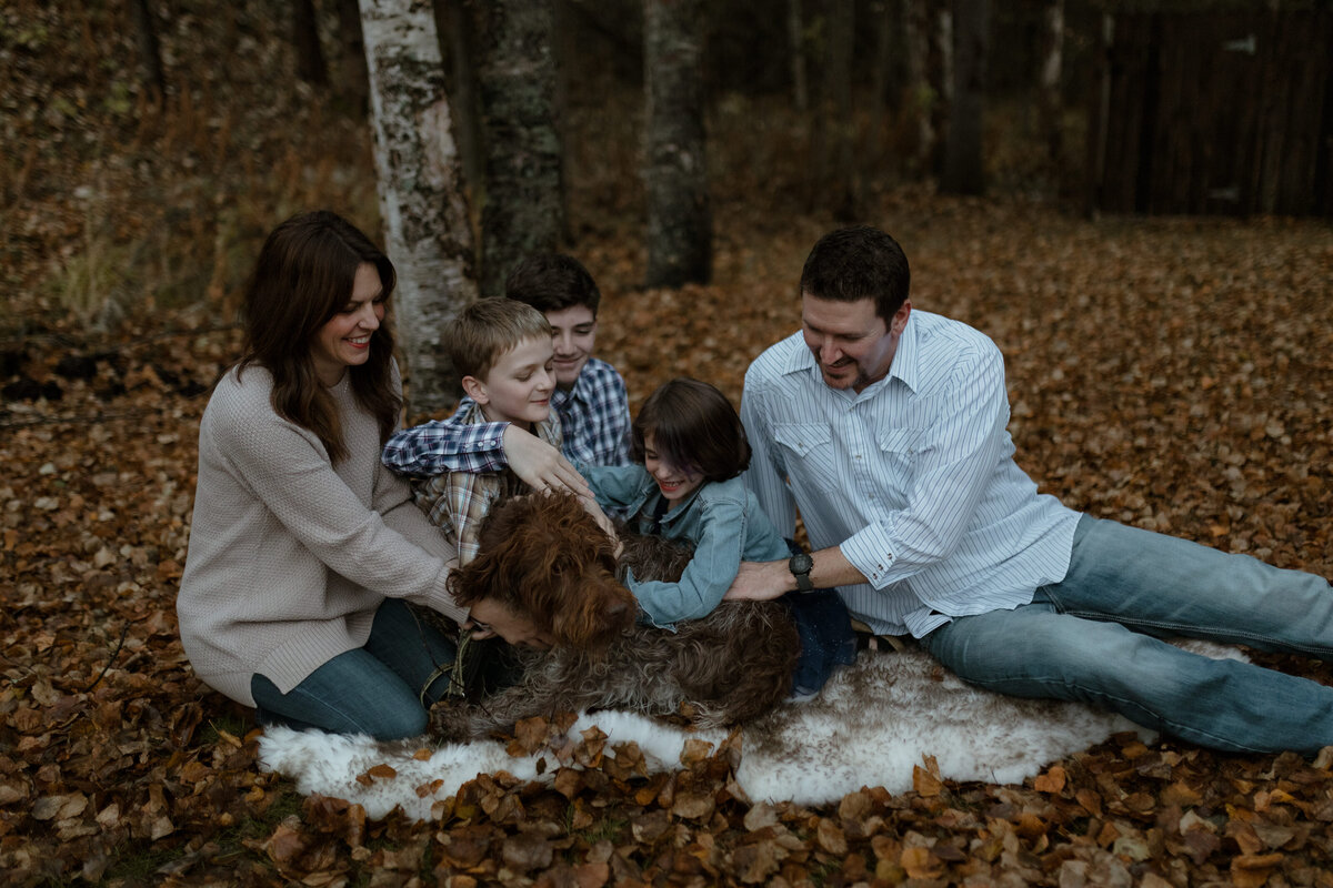 Family playing with dog in fall leaves