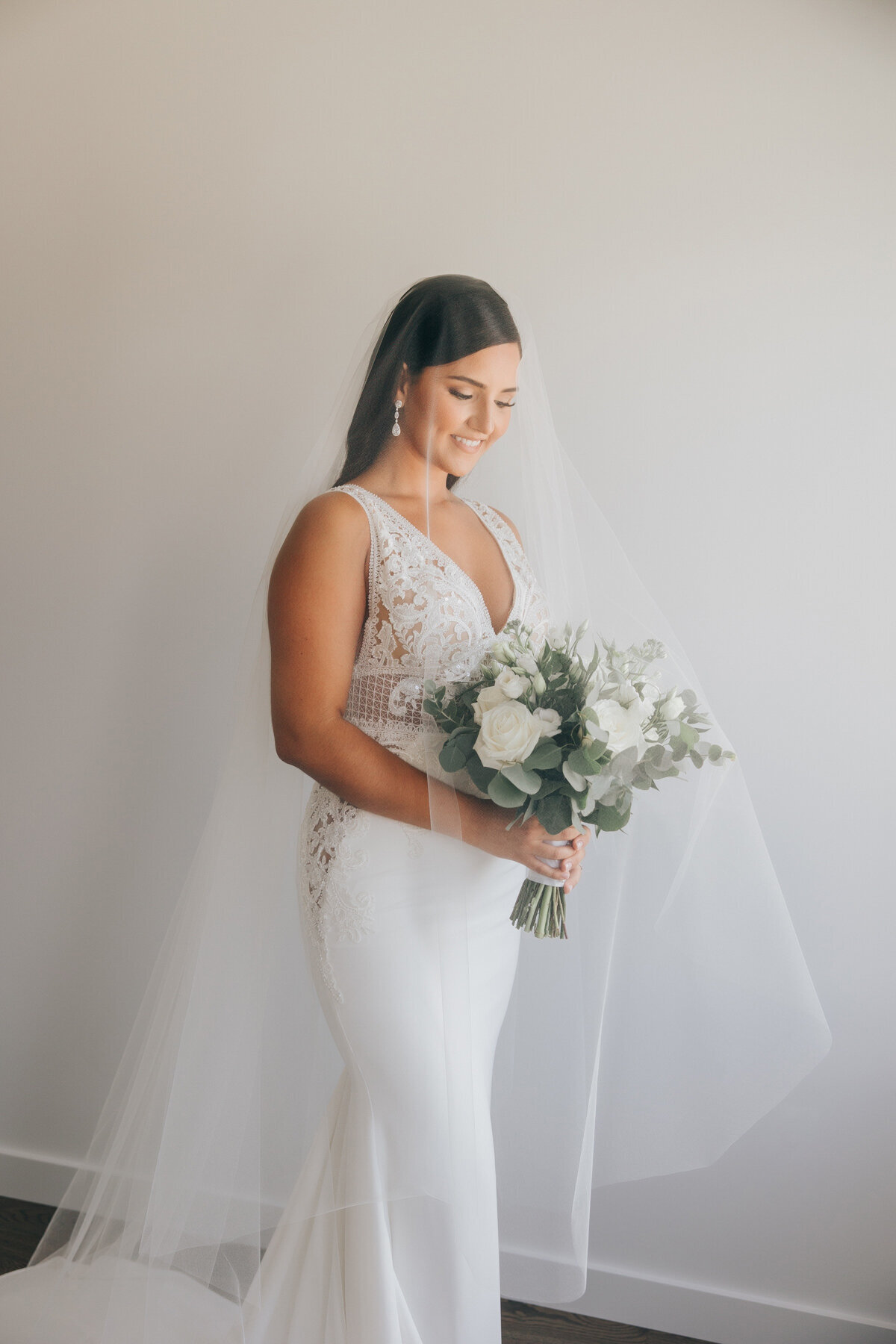 Elegant bride posing in her white wedding dress while holding her white wedding bouquet