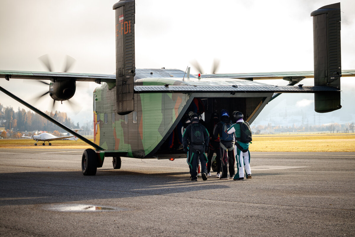 Die Pink Skyvan  steht am Boden. Zu sehen ist das Flugzeug . Die bunte und auffällige Lackierung sticht heraus. Fallschirmspringer steigen ein
