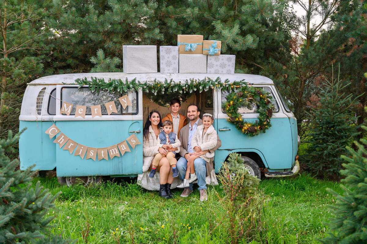 mom and dad sitting in a VW bus with their two sons and daughter for their outdoor Christmas family photos in Burlington, Ontario.