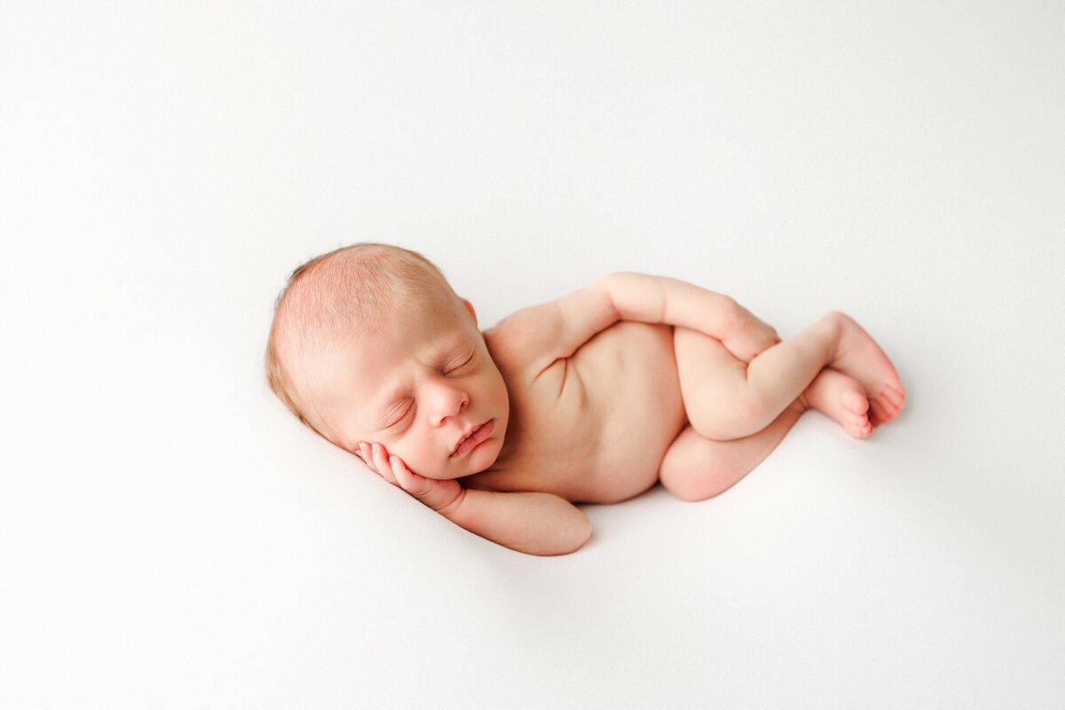 Sweet image of a newborn baby boy gently posed on his side by Angelia Jansen, owner of One Good Shot Photography