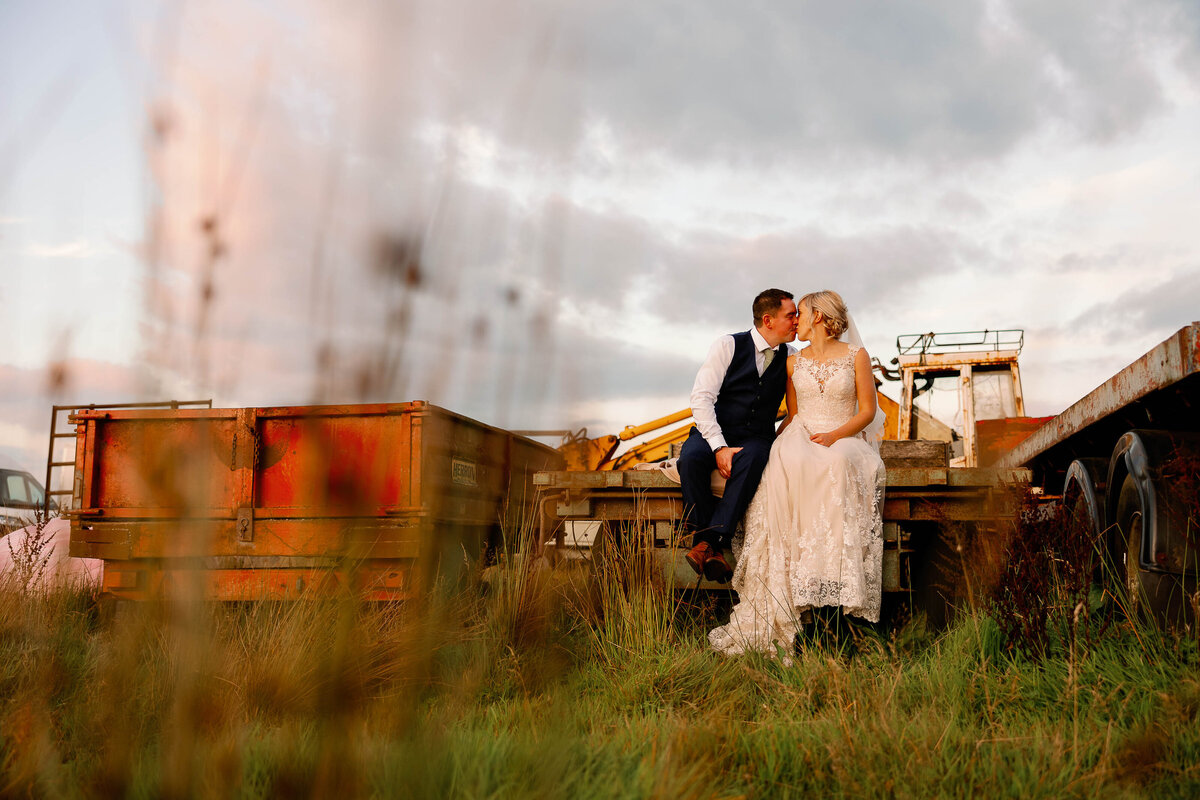 Couple sat together kissing on Farm Machinery at their Haworth Wedding