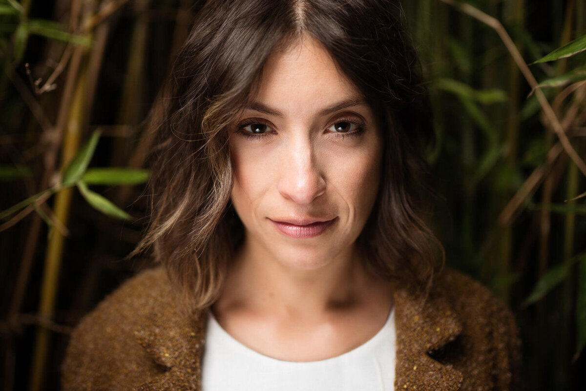 Close-up portrait of a woman in a bamboo garden, gazing deeply into the camera.