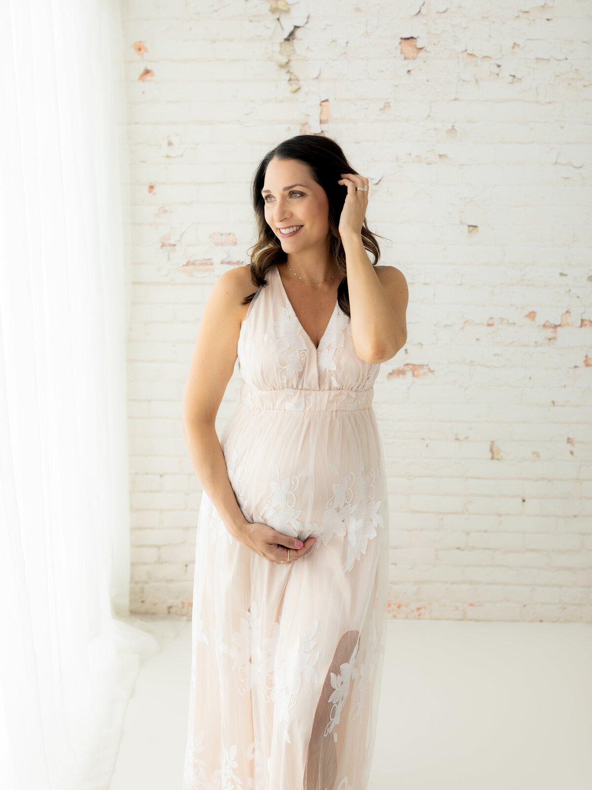 pregnant mother in cream maternity gown holding baby bump for maternity photoshoot