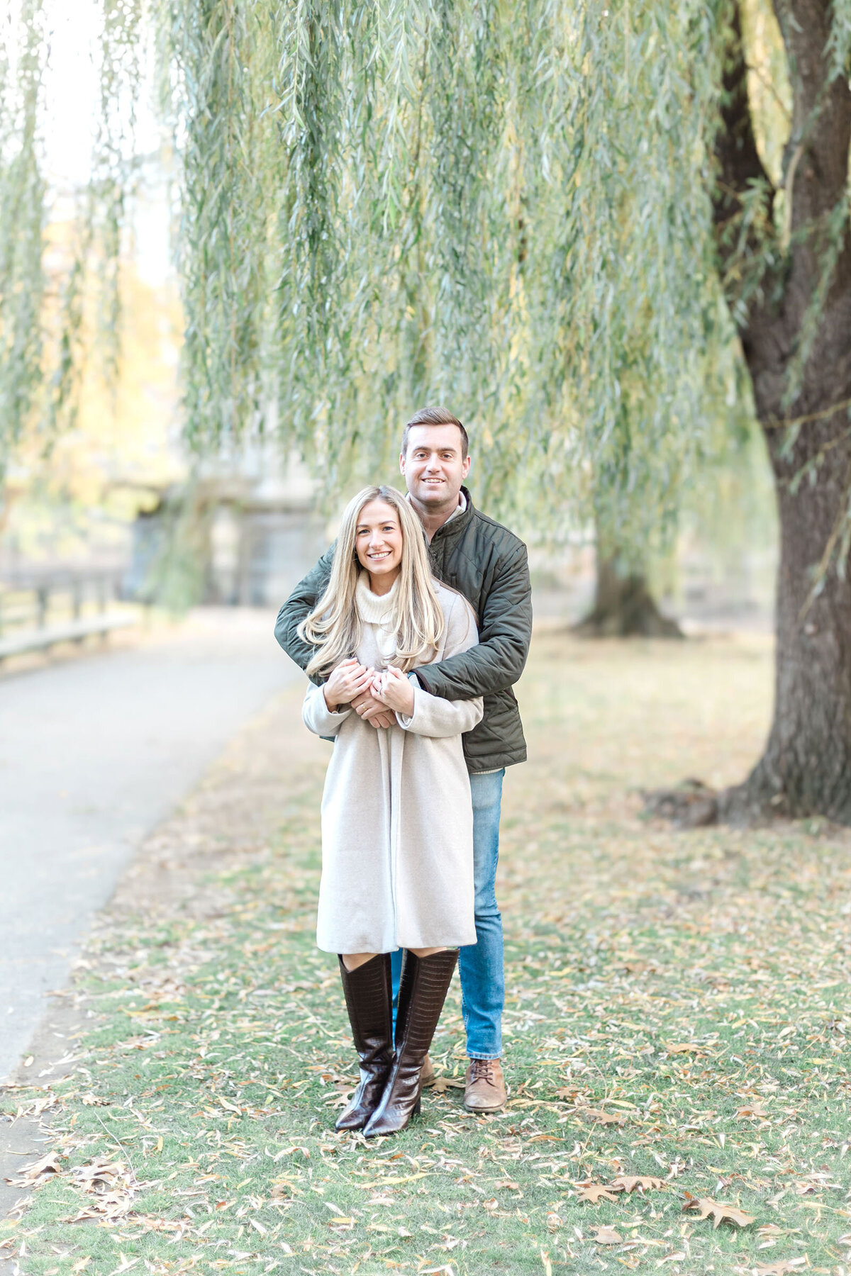A couple embraces by the willow trees in teh Boston Public Garden
