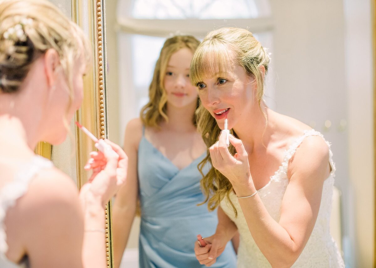 Disney bride applying lipstick in mirror at Disney Wedding Pavilion
