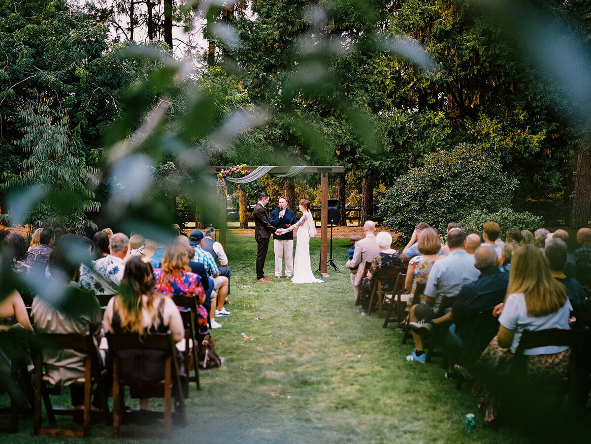 Outdoor wedding ceremony showing bride and groom at altar and seated guests. 