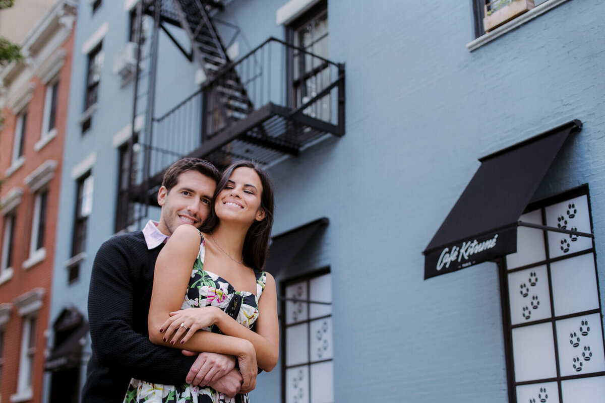 The fiancé is lovingly hugging his fiancée from the back, in West Village, Manhattan, NYC. Image by Jenny Fu Studio.