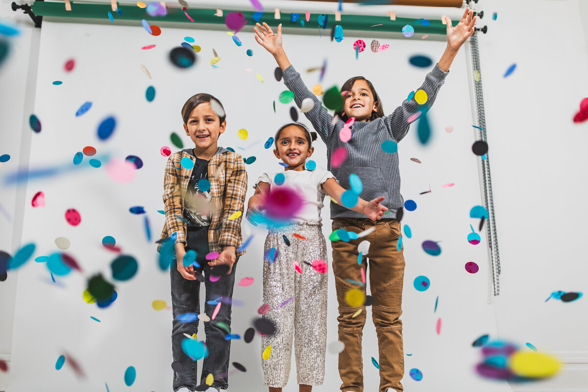 During a fun stylized portrait photography session in Pittsburgh Pennsylvania children's throw colorful confetti into the air and smile