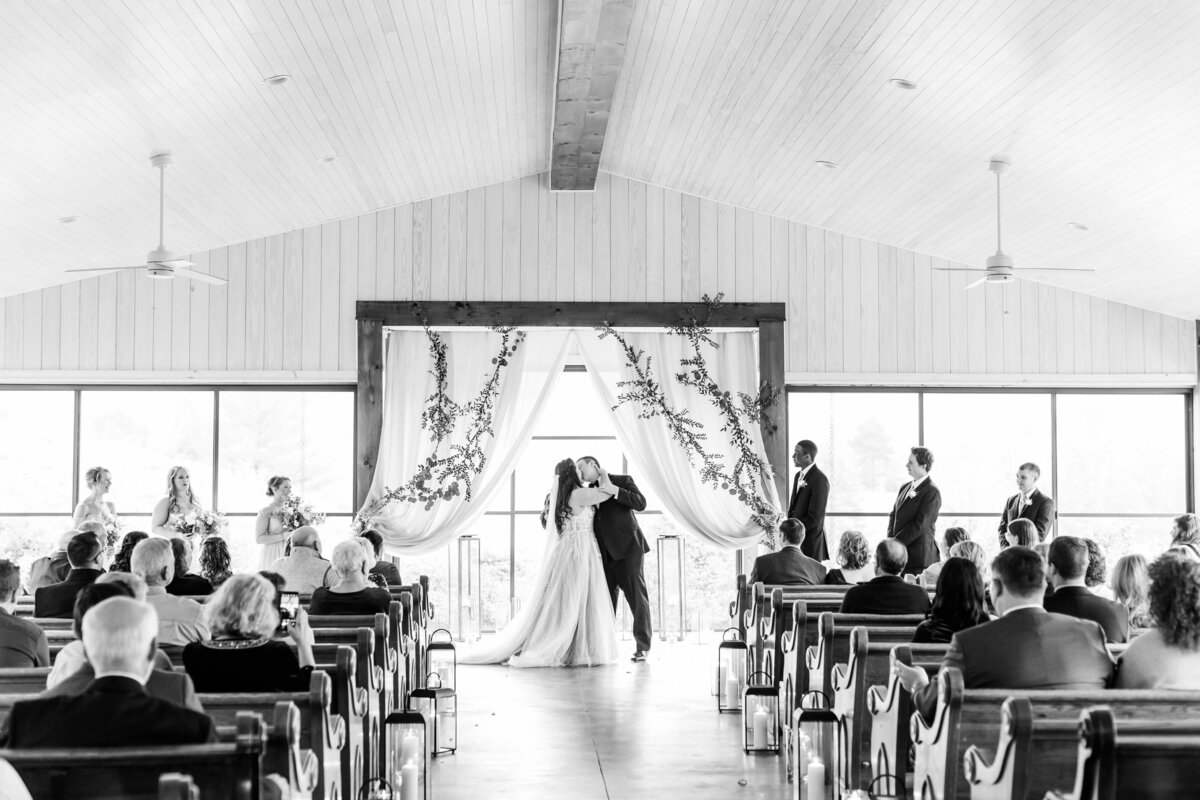 black and white photo of couple kissing at ceremony