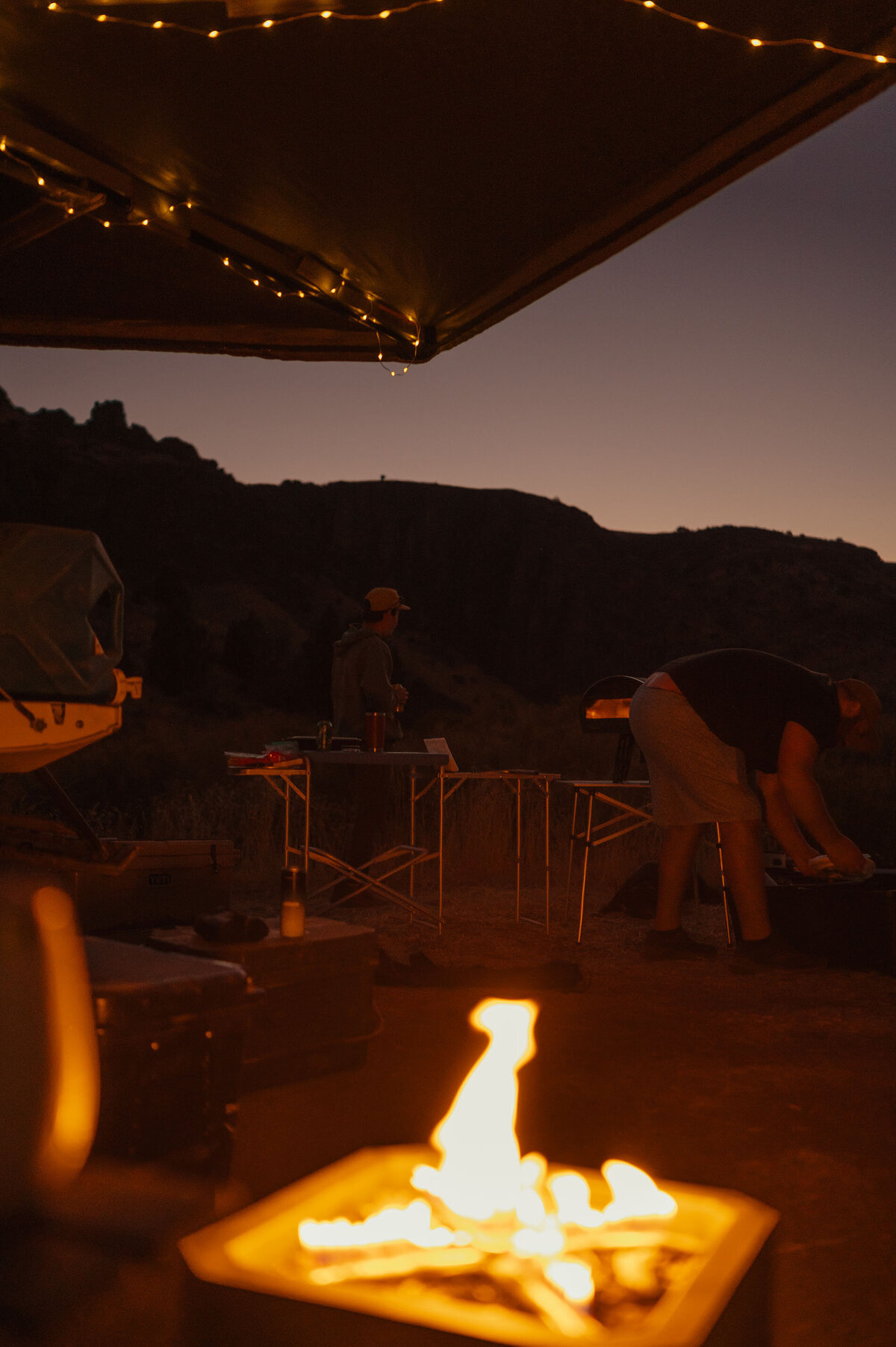 people standing around a bonfire at dusk after an overland elopement in Moab, Utah