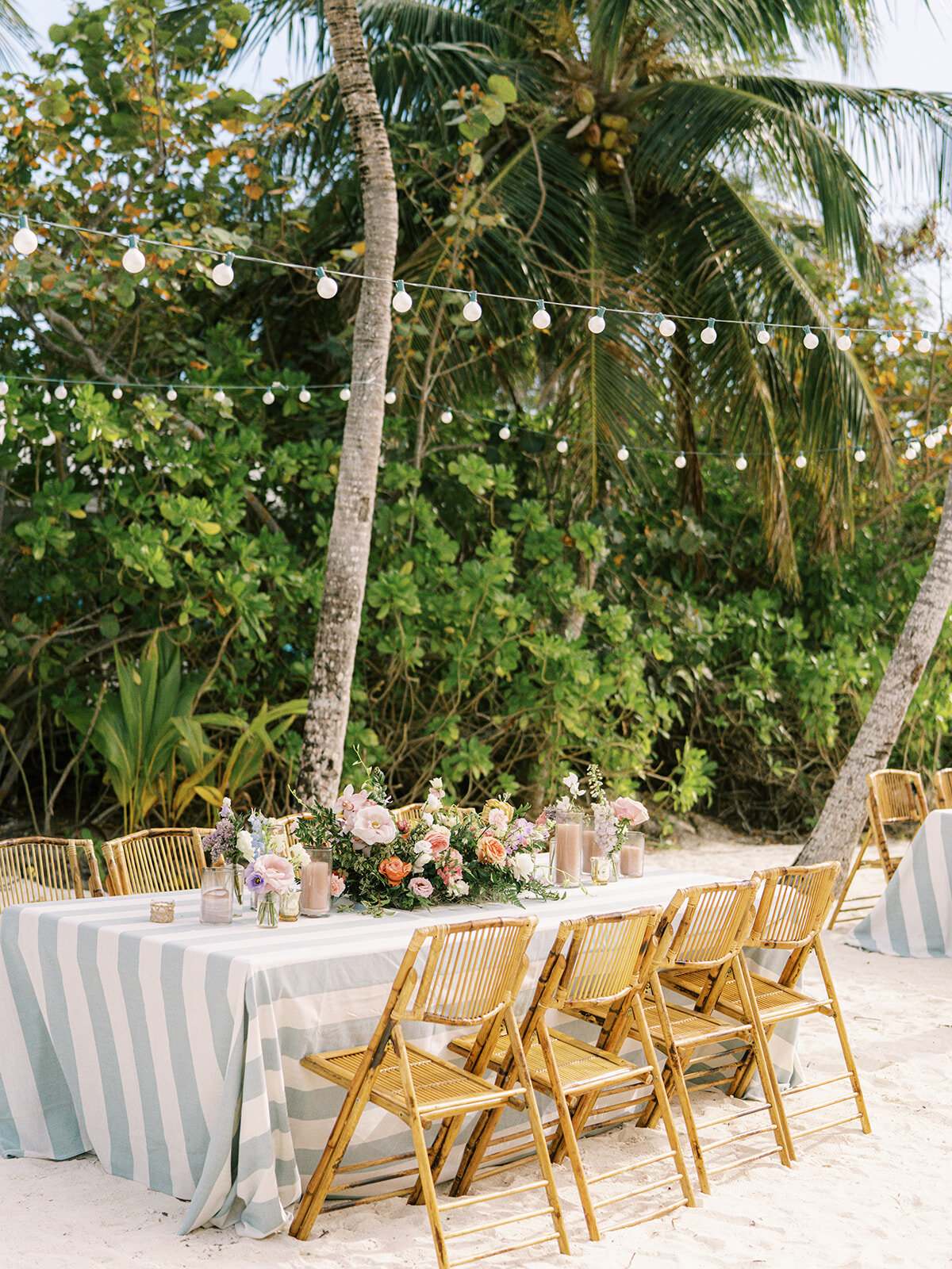 Tropical table floral meadows consisting of orchids, and roses in peach, pink, dusty blue, pale yellow, orange, and green tones. Exuma, Bahamas destination wedding reception tropical floral design. Spring beach wedding floral design by Rosemary & Finch Floral Design.