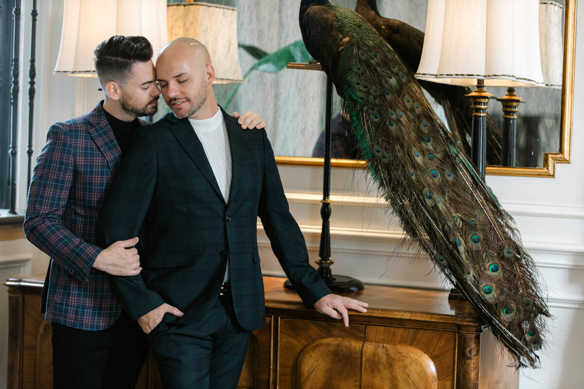 Two grooms at The Mason in Dallas during their engagement session, in a stylish and romantic pose, snuggling into each other.