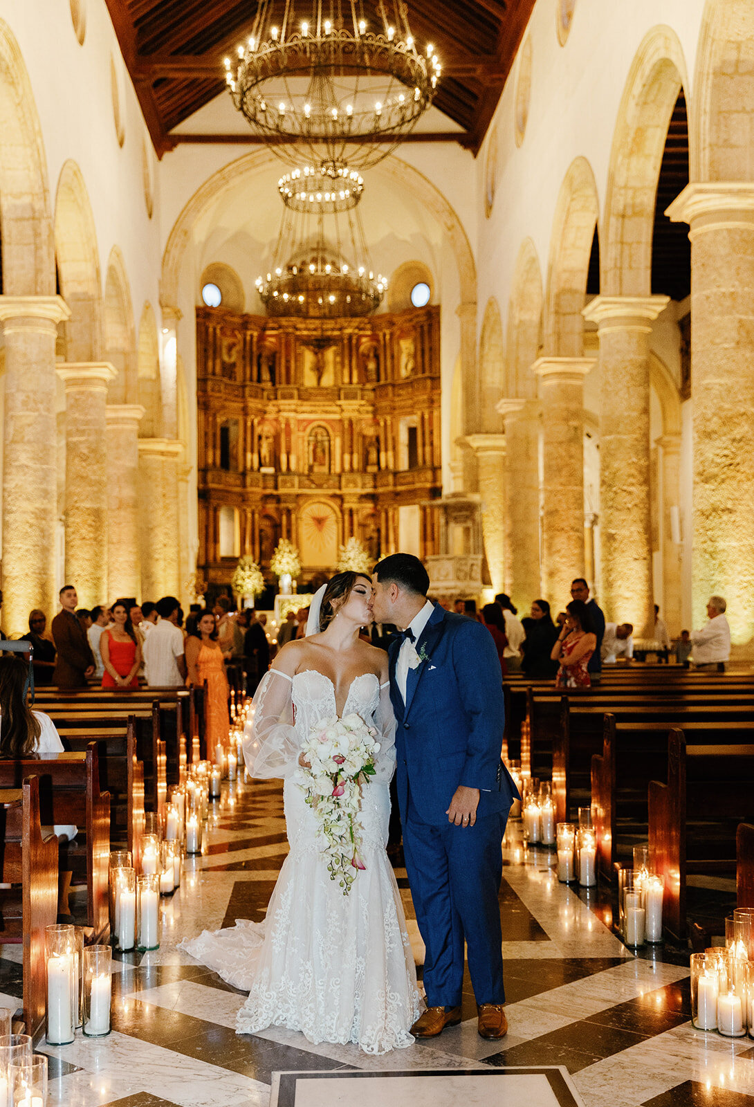 Victoria and Daniel share a romantic kiss in the candlelit aisle of their Cartagena Colombia wedding ceremony.