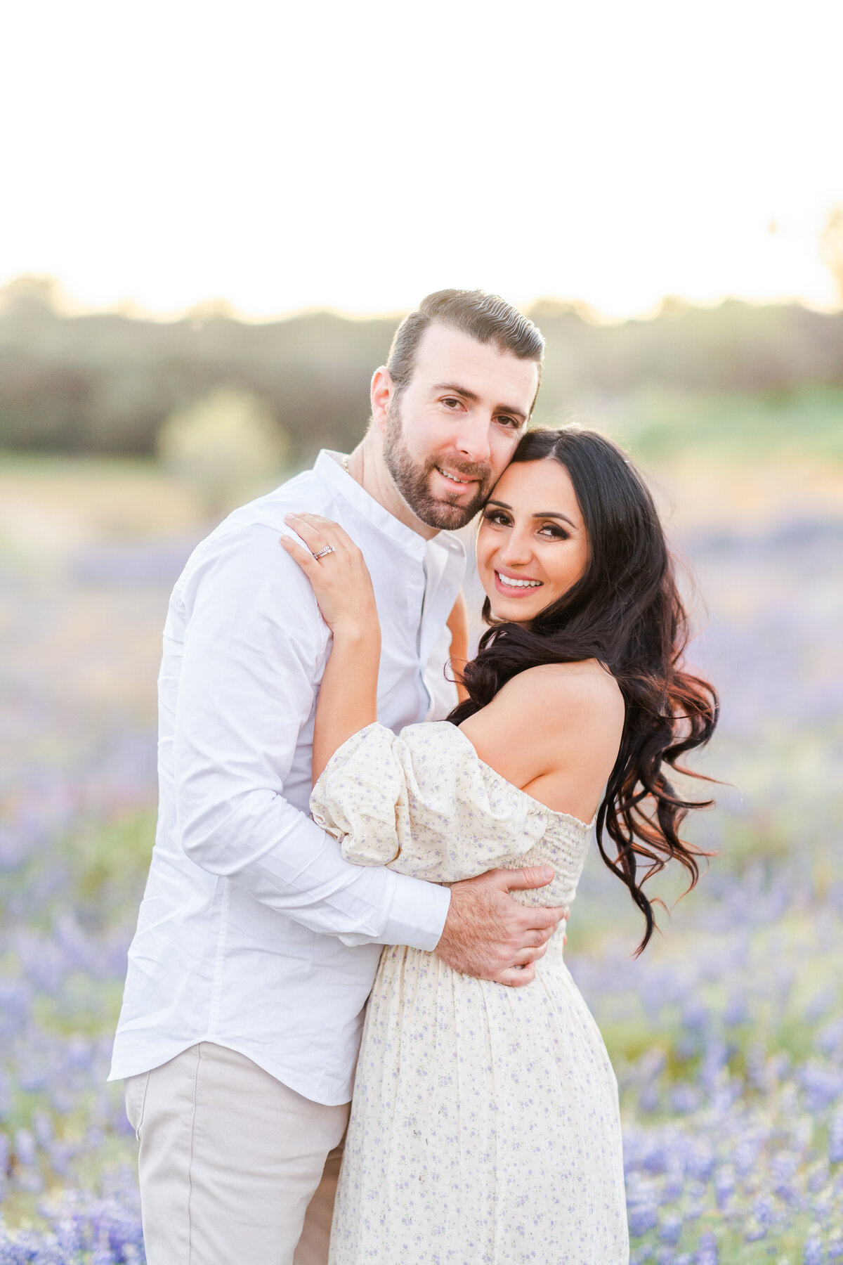 A couple stands embracing one another in a field of purple lupines photographed by bay area photographer, Light Livin Photography.