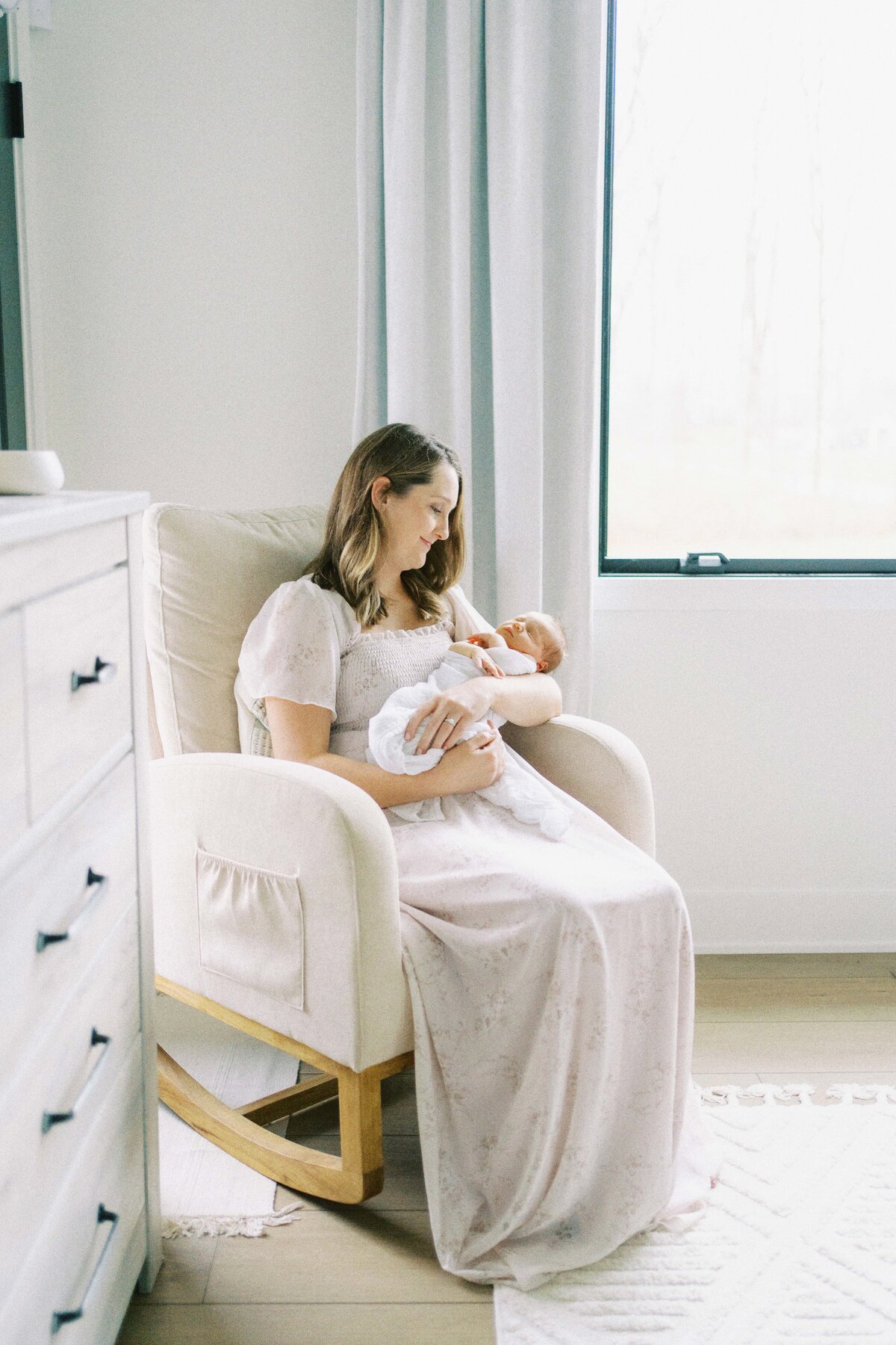 mom sitting in chair rocking baby