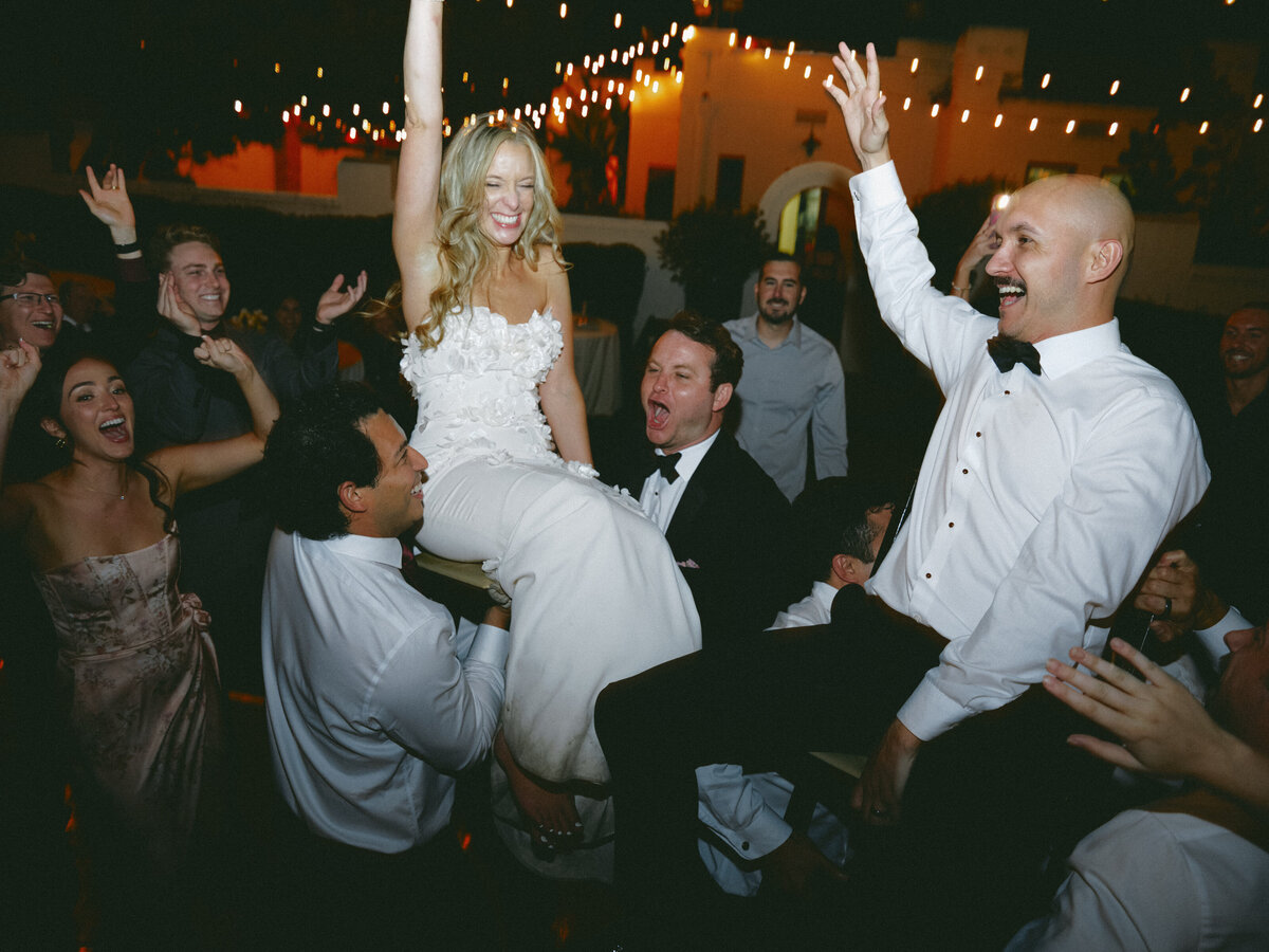 Bride and groom being lifted up at wedding reception