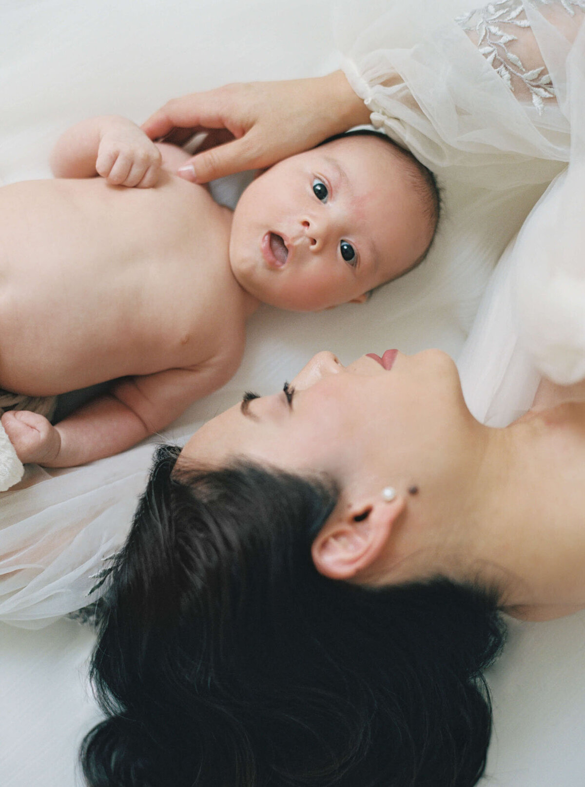 Mother on bed with baby for candid newborn photography San Francisco Bay Area.