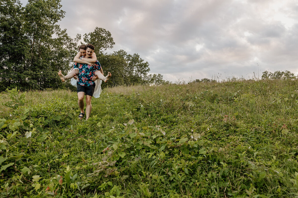 A person running through a field holding their partner on their back