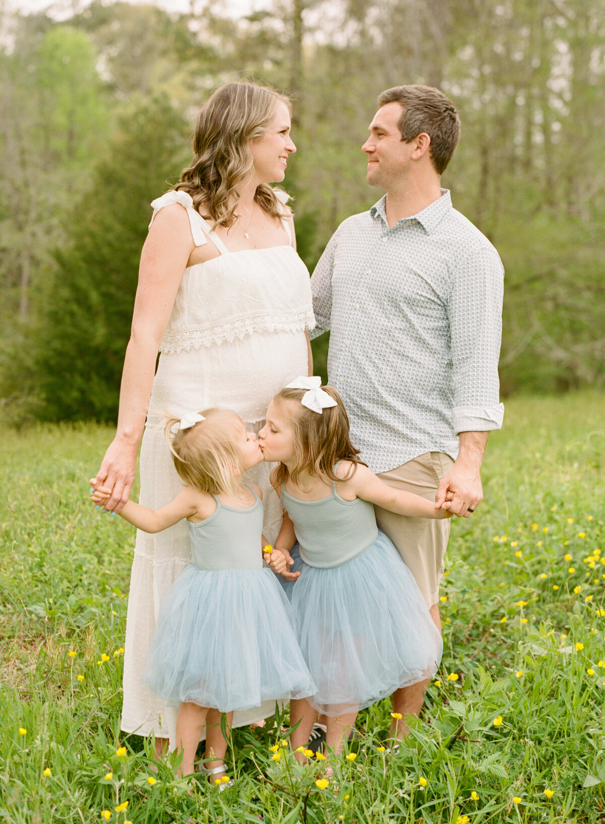 Family plays and smiles in a field during their maternity session at Joyner Park in Wake Forest. Photographed by Raleigh Maternity Photographer A.J. Dunlap Photography.