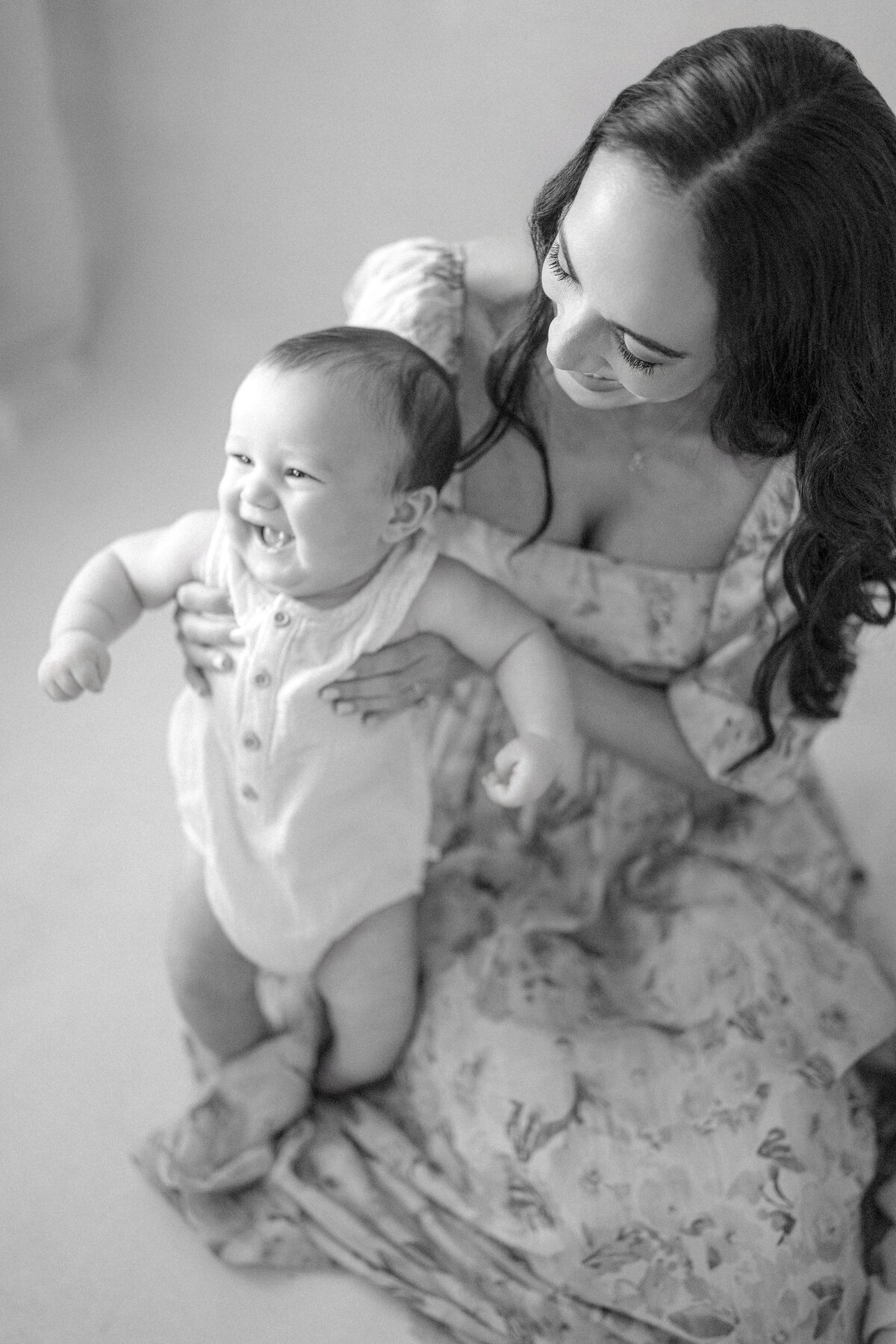 Tampa 6-month milestone portrait of smiling baby boy and mother in natural light studio
