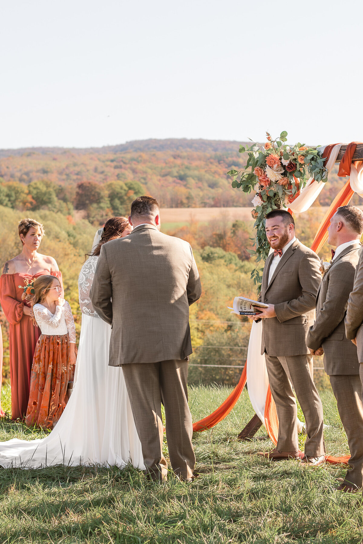 Bride and groom exchanging vows during a fall outdoor wedding ceremony with floral arch and mountain views outside of Pittsburgh.
