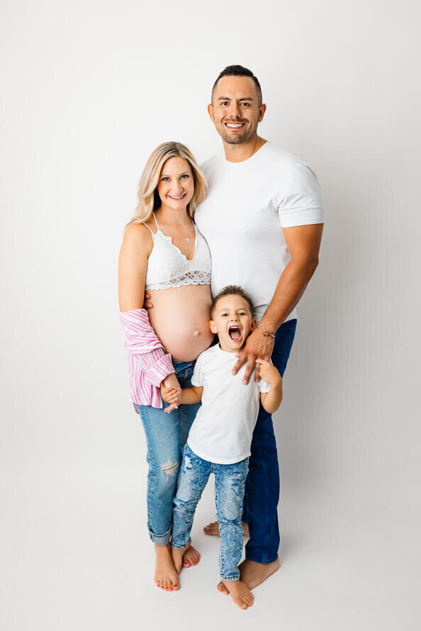 A pregnant woman and her husband a small son pose for the camera.