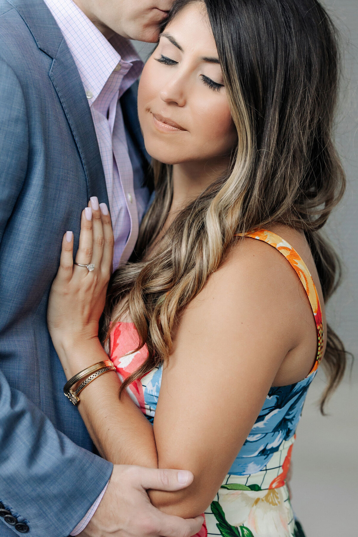 Close up of the bride as the groom kisses her temple during their Dallas engagement session
